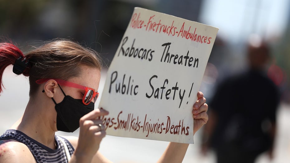 protestor holds sign against robotaxis