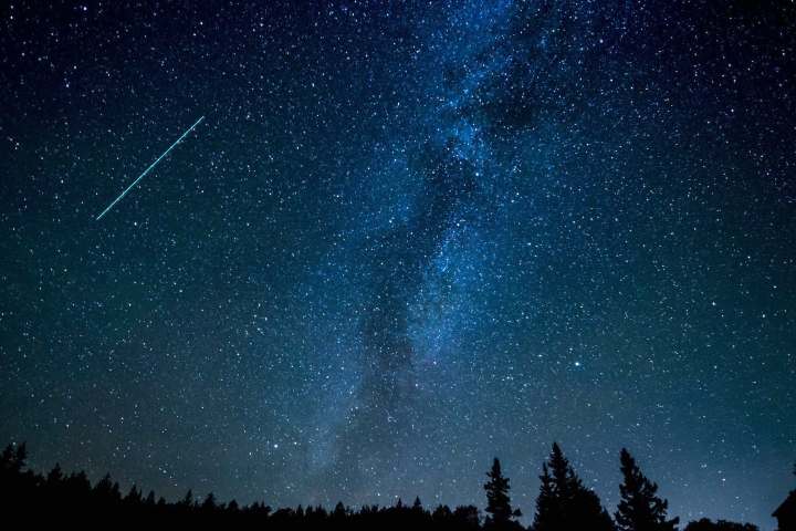 A shooting star streaks across the night sky.