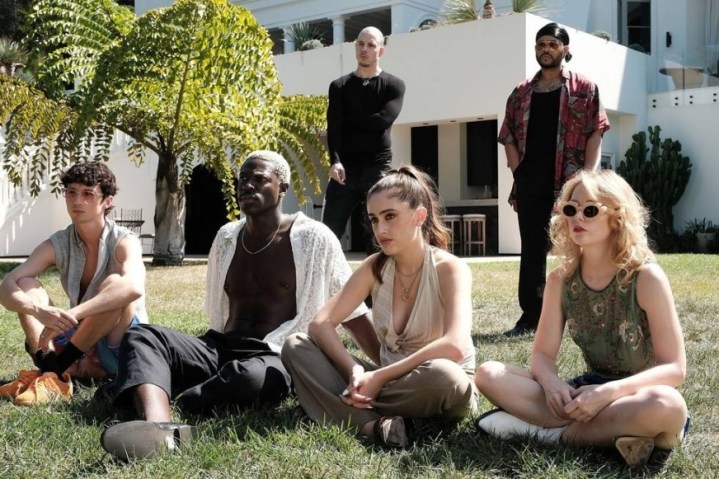 6 people sit and stand on a lawn in The Idol.