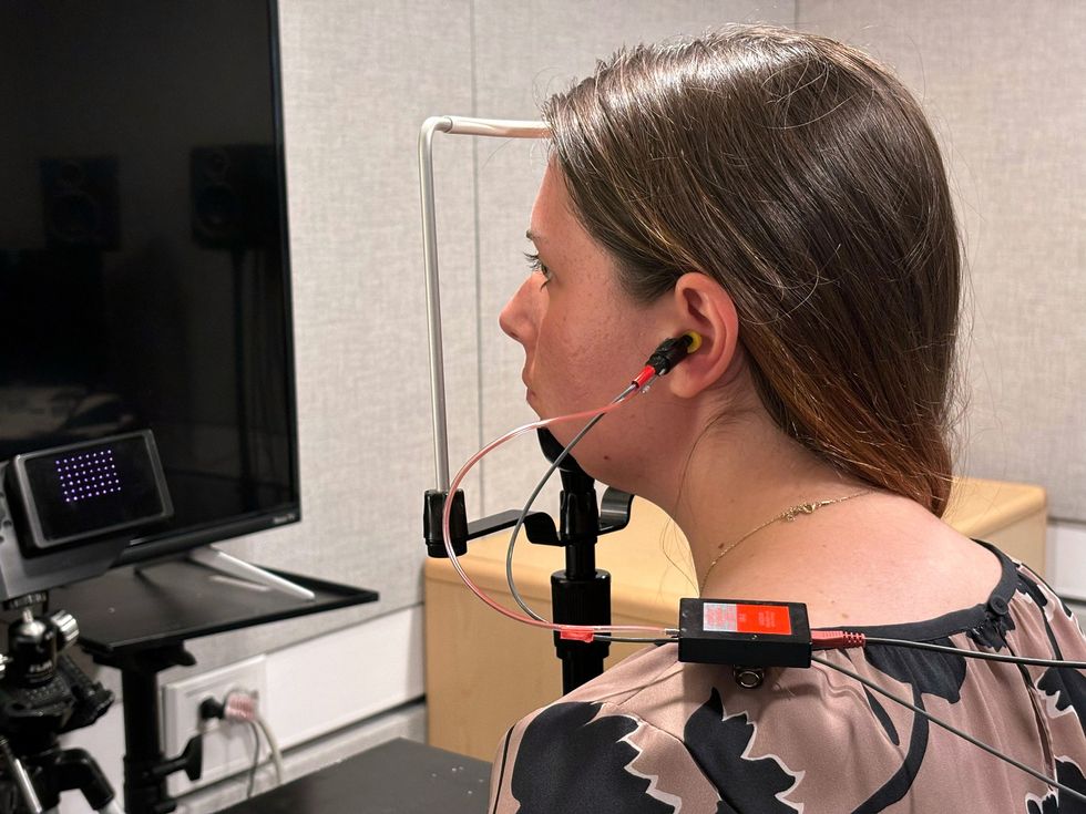 woman sitting at a desk with earphone in ear and looking at a screen