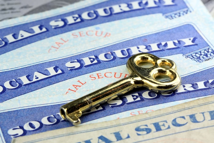 Brass key on top of four Social Security cards.