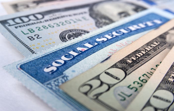 A Social Security card wedged between a fanned pile of assorted cash bills. 