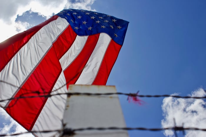 A large American flag hung behind a fence with barbed wire. 