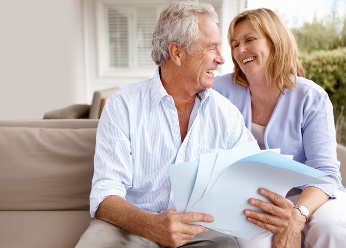 Two people looking at each other laughing while one holds papers.