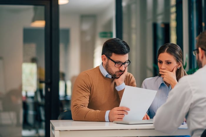 Couple seemingly not happy about information provided to them by professional in office.