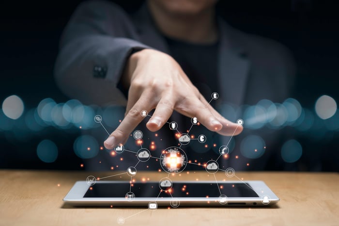 Digital icons hover above a tablet laying on a desk.