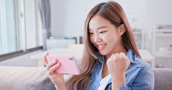 A person looks at a smartphone and smiles.