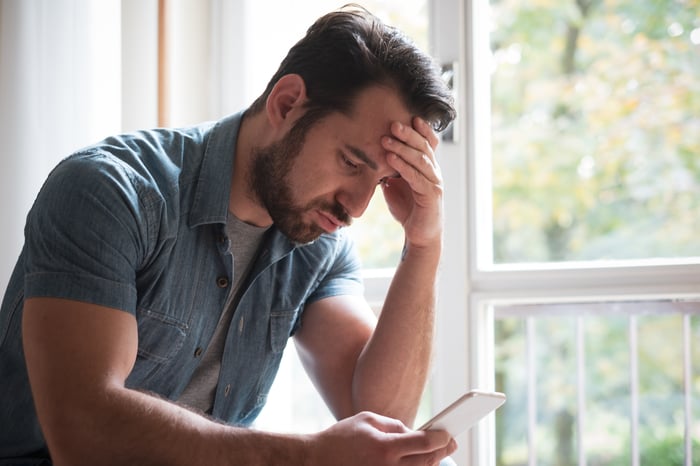 A disappointed-looking person staring at a phone. 