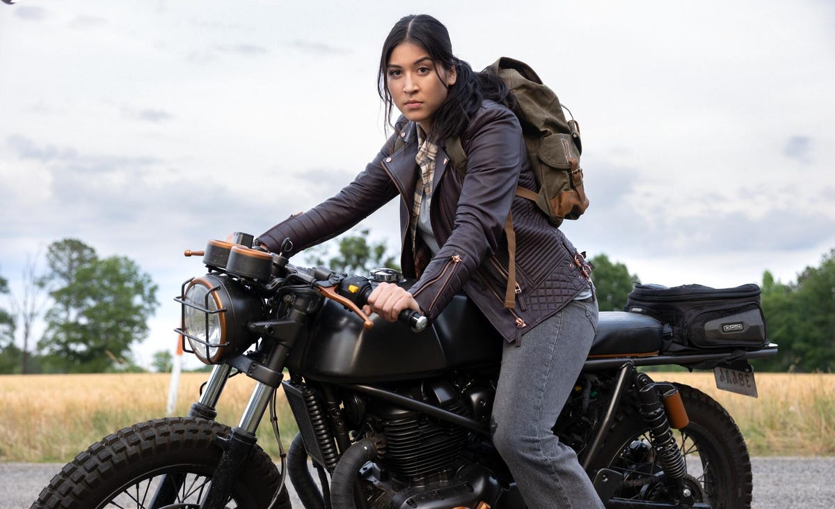 woman with backpack sits on motorcycle