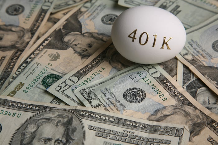 An egg with 401k written on it, sitting on a pile of cash.