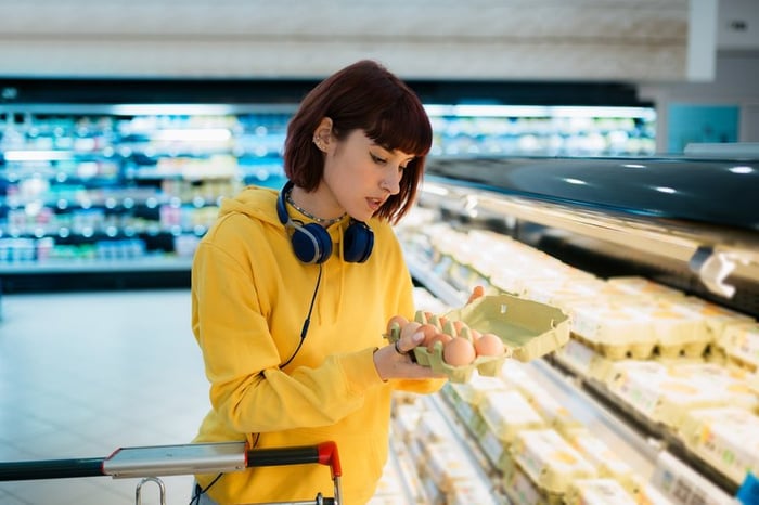 Shopper inspecting a carton of eggs in the grocery store.