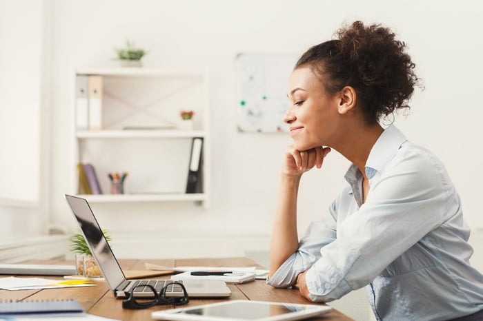 A woman smiling at her office desk.