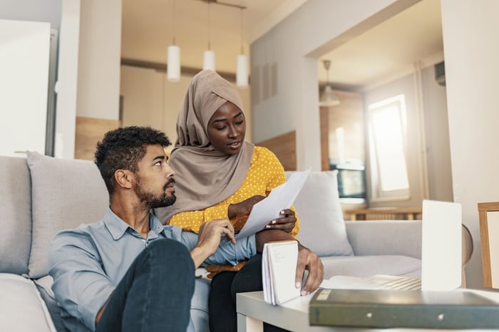 Two people looking over their bills while sitting on their living room couch.