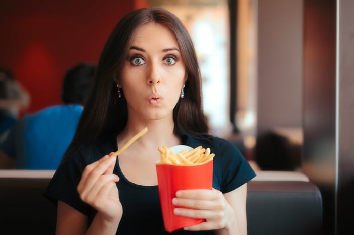 Someone eating fries at a restaurant.