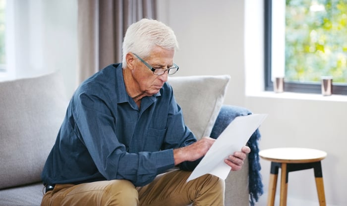 A person on a couch is holding a document.