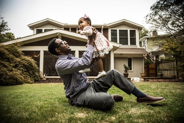 Father and toddler daughter play in home's backyard.