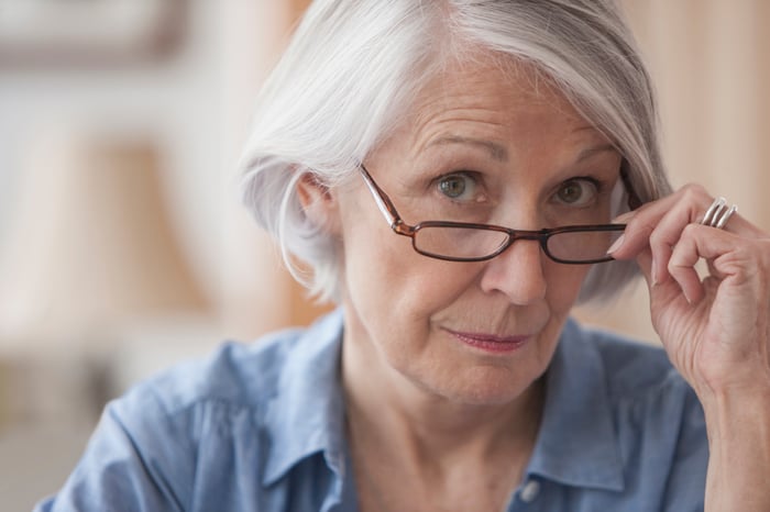 A person pulling their eyeglasses down onto the bridge of their nose.