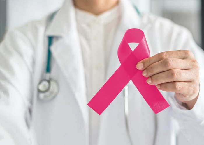 A doctor holding up the pink breast cancer awareness ribbon