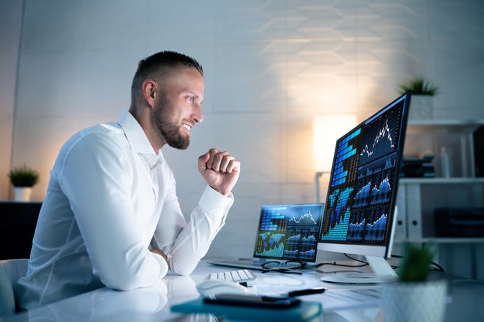 An excited investor looks at financial charts on computer.