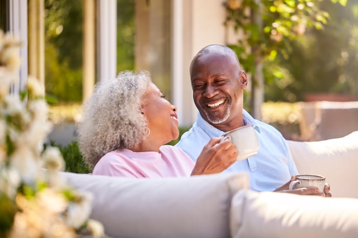 Two people sitting on a couch each holding a coffee mug.