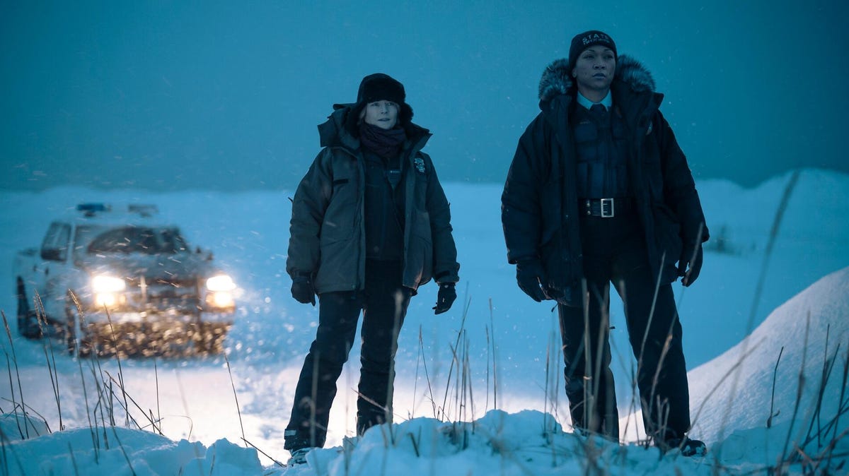 Two women police officers stand outside in the snow.