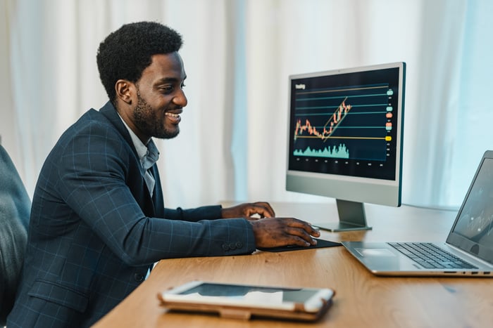 Smiling person looking at graphs on a computer.