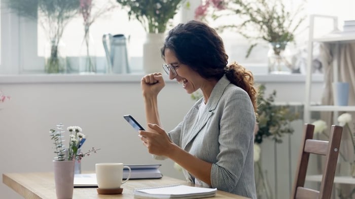 A person is excited while looking at their phone screen.