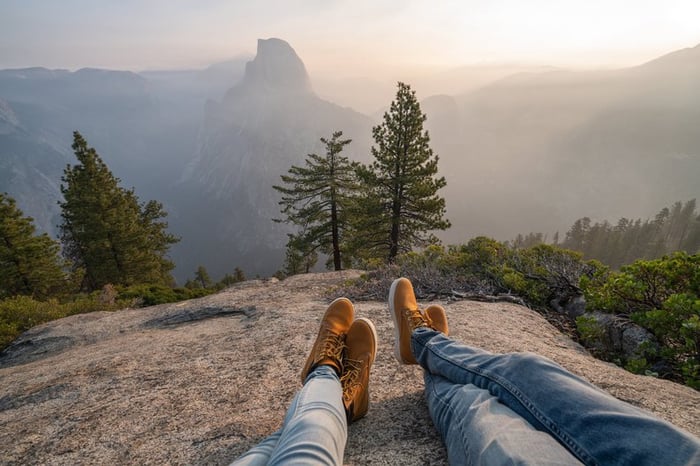 Two people lying on a rock in overlooking trees and Half Dome in Yosemite.