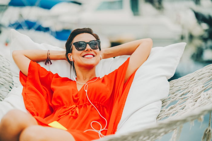 A person smiles in a hammock with their hands behind their head.