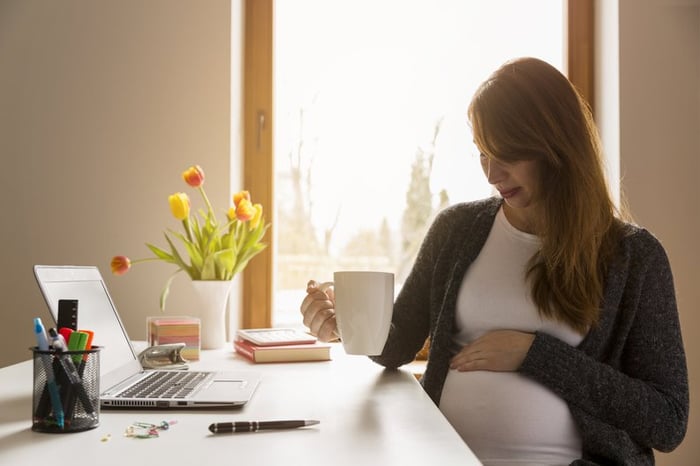 Pregnant woman sitting at her desk.