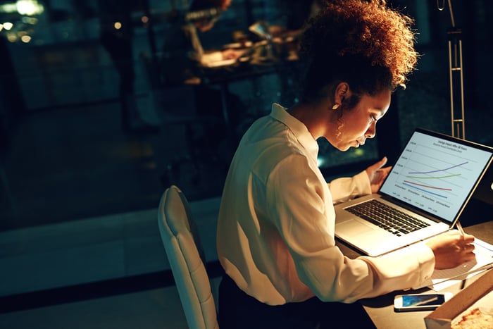 An investor looks at a chart on a laptop in a darkened office.