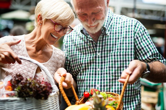 A retired couple looking at a basket of flowers.