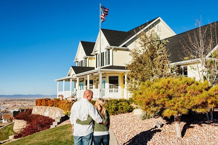 Couple standing outside admiring a large, impressive looking home.