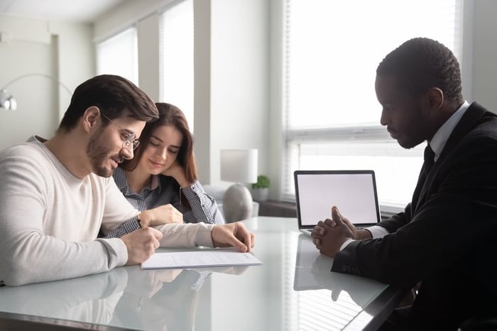 Couple signing paperwork with an agent.