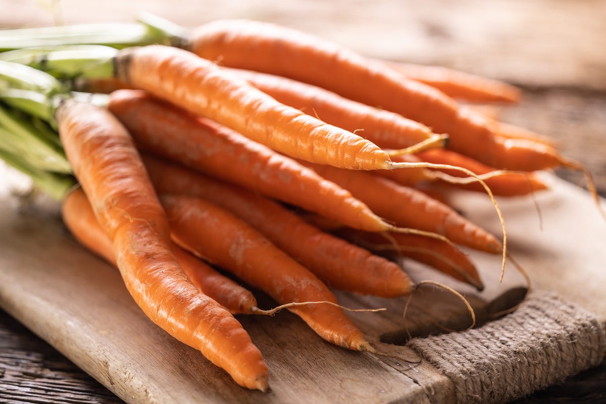 Fresh carrots on a wooden cutting board.