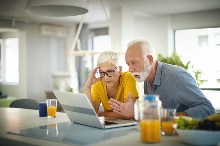 Two people with concerned facial expressions looking at a laptop.