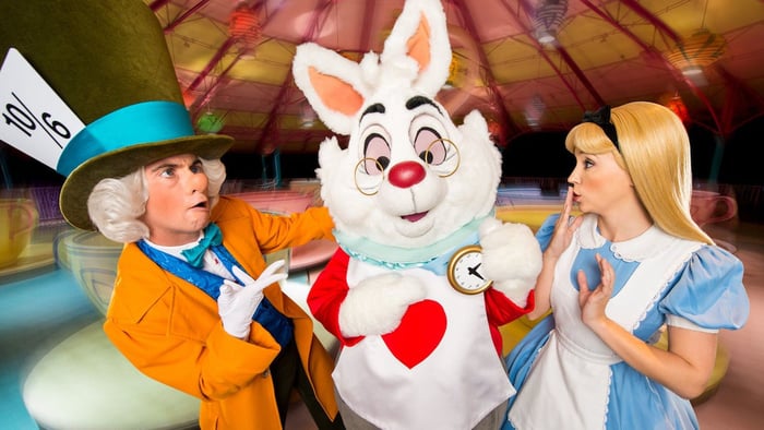 Mad Hatter, Rabbit, and Alice look confused in front of their spinning teacup ride at Disney's Magic Kingdom.