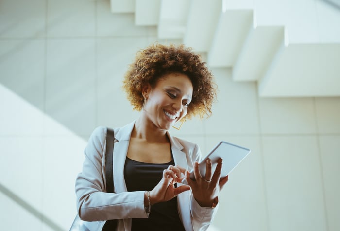 A smiling person looks at a something on a phone in a stairwell.