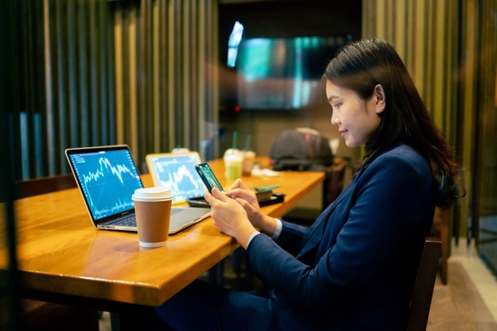 A person siting at a desk looking at graphs on multiple device monitors.