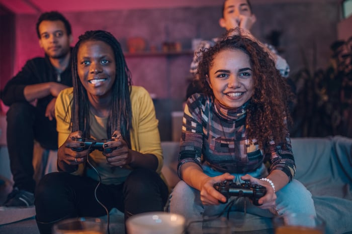 Friends sitting on the couch playing video games.