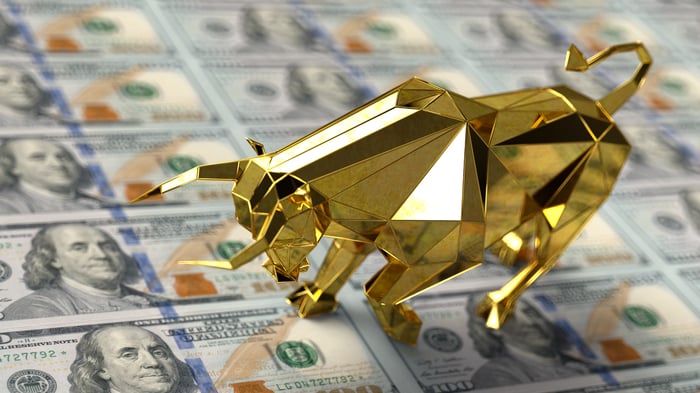 A golden bull figurine on top of a strip of money.