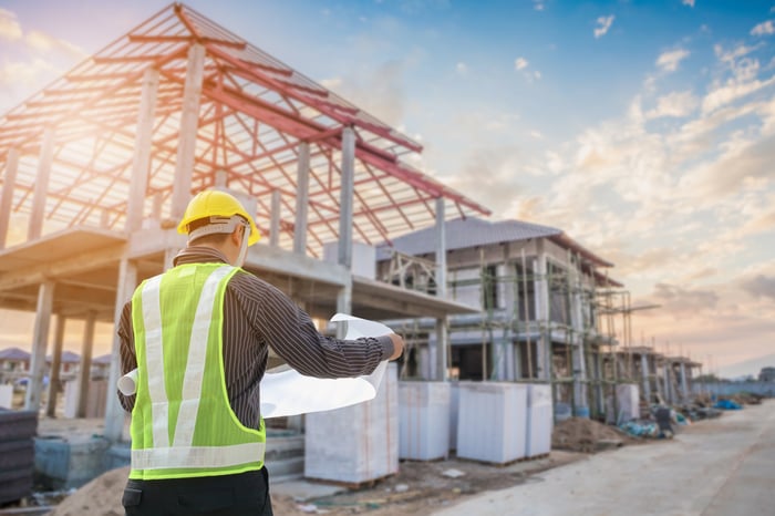 A construction worker standing in front of a building under construction.