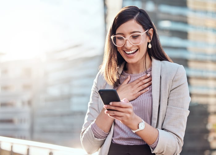 Investor with smartphone looking surprised.