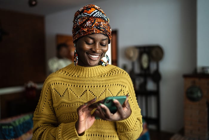 Smiling person typing on smartphone.