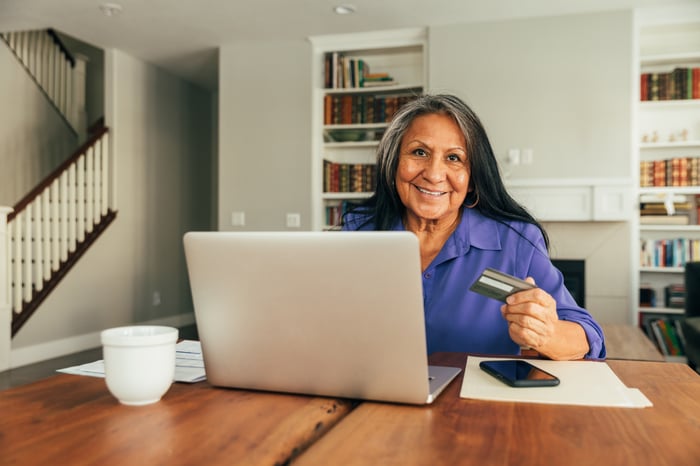 Person in front of a computer holding a credit card.