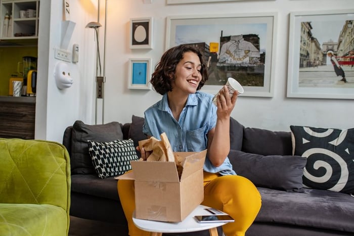 Smiling woman on couch looks at a mug she's getting out of a box