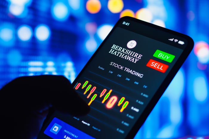 A person holding a smart phone with Berkshire Hathaway stock in the display.