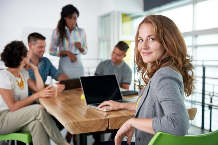 Young smiling investor with laptop in meeting.