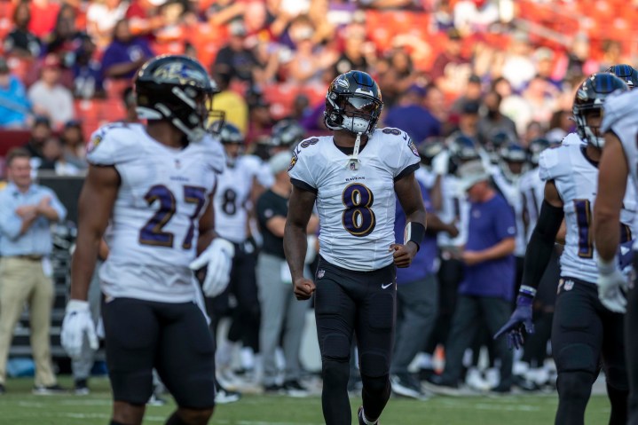 Lamar Jackson of the Baltimore Ravens runs into the huddle on a football field.