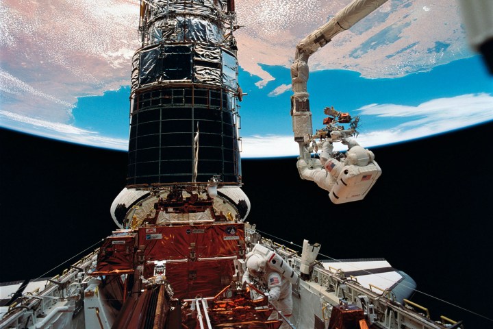 Astronaut F. Story Musgrave, anchored on the end of the Remote Manipulator System (RMS) arm, prepares to be elevated to the top of the towering Hubble Space Telescope to install protective covers on magnetometers. Astronaut Jeffrey A. Hoffman assisted Musgrave with final servicing tasks on the telescope, wrapping up five days of extravehicular activities (EVA) during the first servicing mission in 1990.